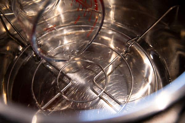 pouring water into an instant pot with a glass measuring cup