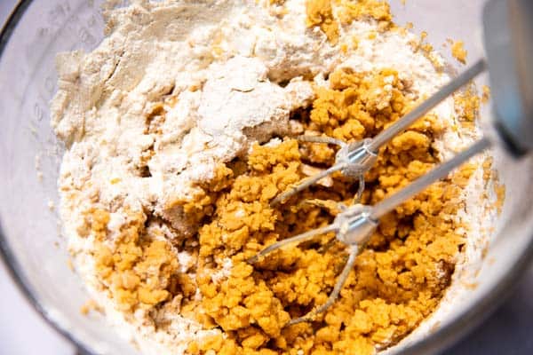 flour and wet ingredients for cookie dough in a glass bowl with electric mixer