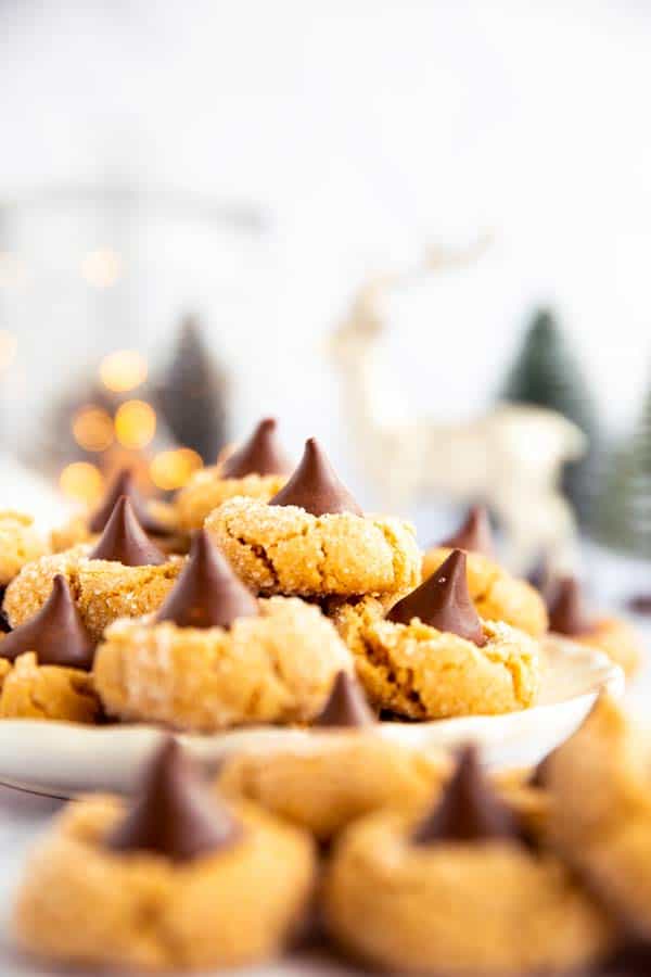 piles of peanut butter blossom cookies on a plate in front of festive decor