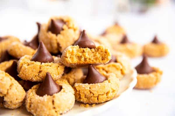 image of a cookie plate with the focus on a halved peanut butter blossom