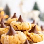 pile of peanut butter blossom cookies on a plate in front of Christmas decor