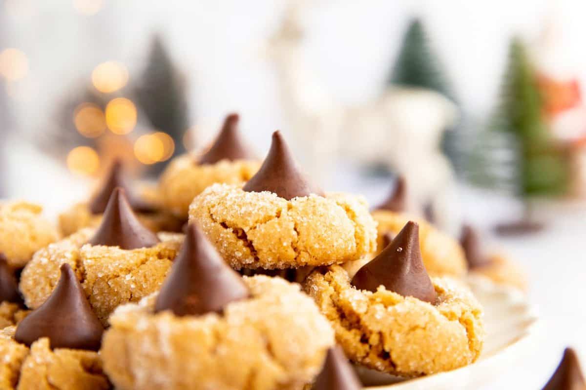 pile of peanut butter blossom cookies on a plate in front of Christmas decor