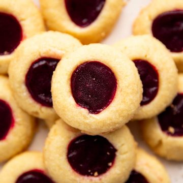 pile of shortbread thumbprint cookies on a cream colored plate