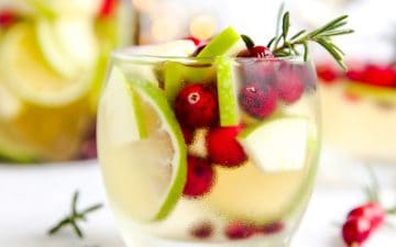 tumbler with lime, cranberry, apple, rosemary and white wine sangria