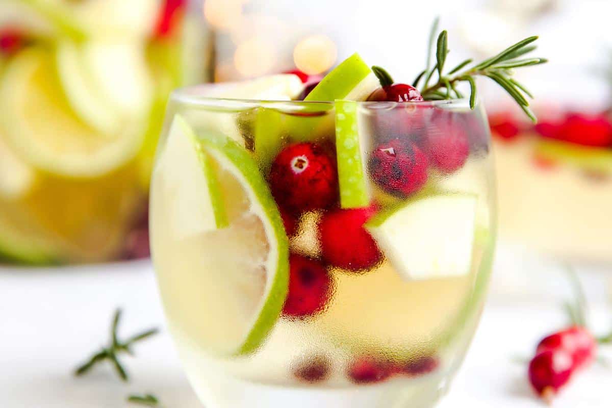 tumbler with lime, cranberry, apple, rosemary and white wine sangria