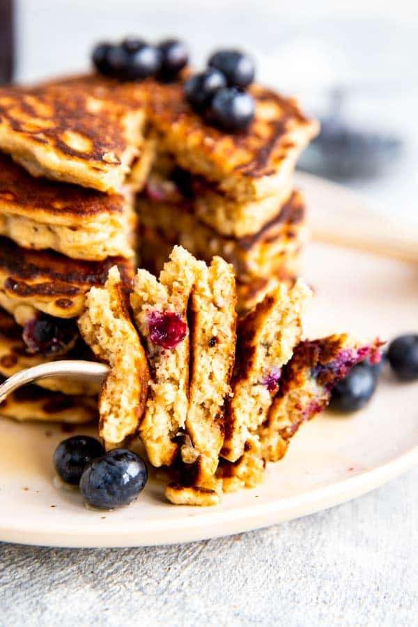 close up photo of a bite taken out of blueberry oatmeal pancakes