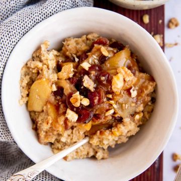 top down view on three white bowls on wooden board filled with oatmeal