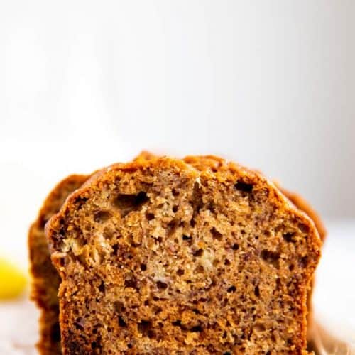 sliced banana bread on a wooden board with a milk bottle and banana in the background