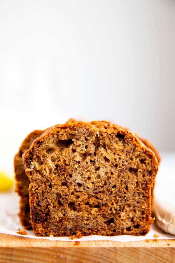 sliced banana bread on a wooden board with a milk bottle and banana in the background