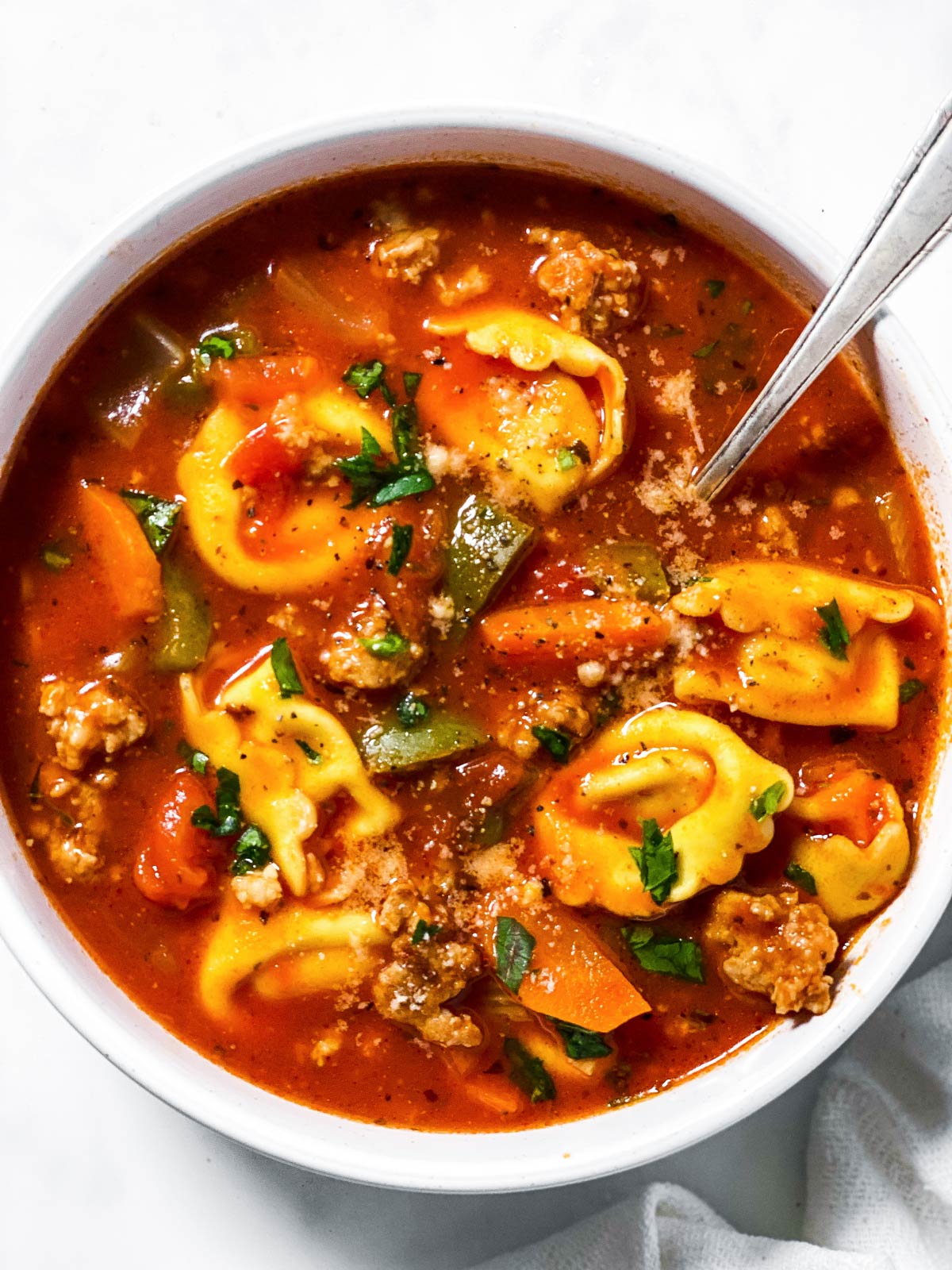 overhead view of sausage tortellini soup in white bowl