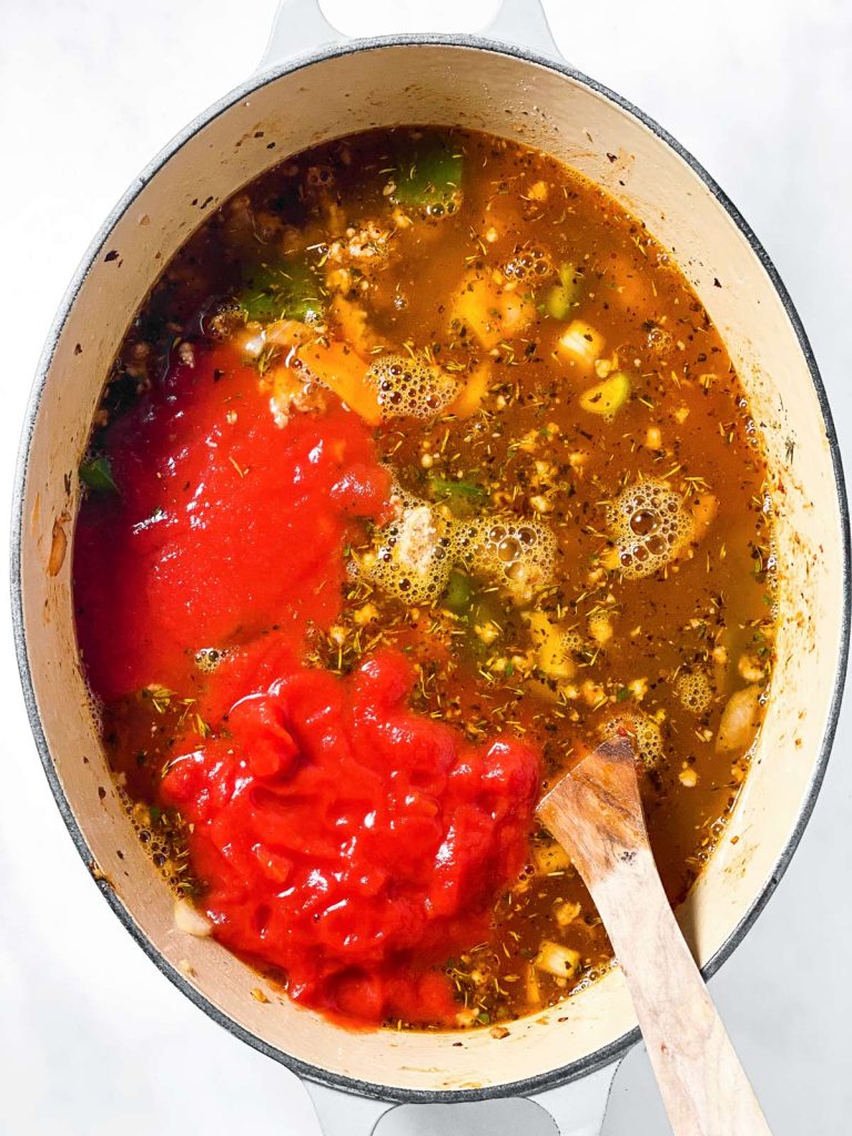 overhead view of sausage tortellini soup ingredients in white Dutch oven