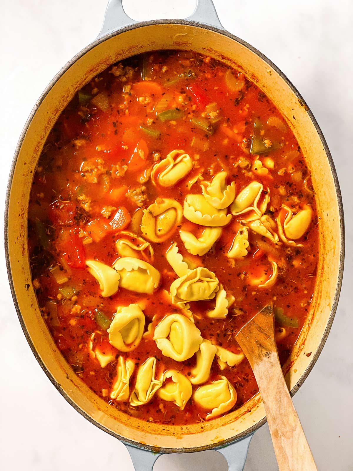 uncooked tortellini in pot with sausage tomato soup