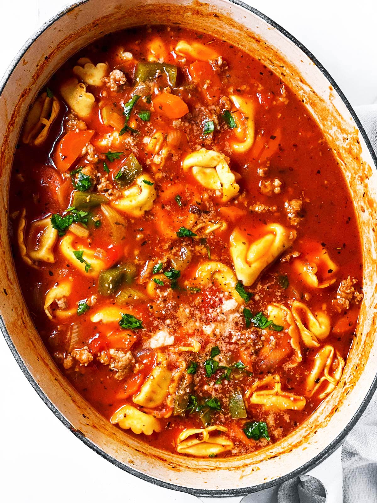 overhead view of sausage tortellini soup in white Dutch oven