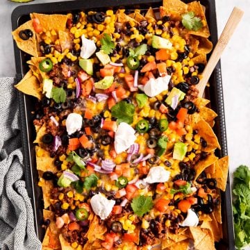 overhead view of nachos on dark colored sheet pan