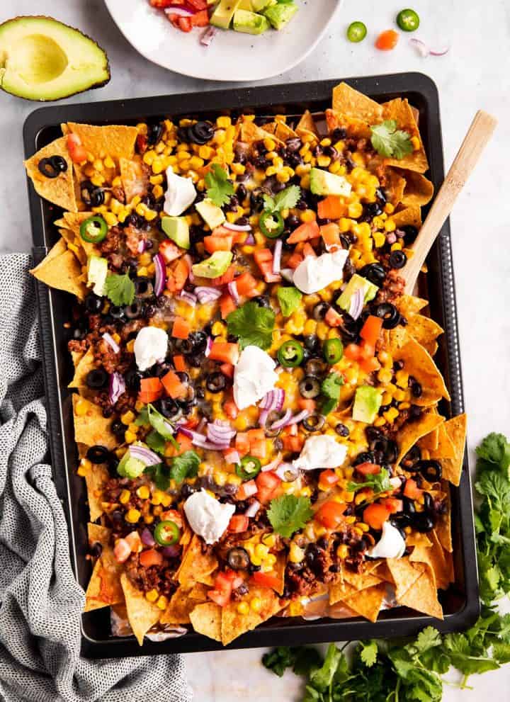 overhead view of nachos on dark colored sheet pan