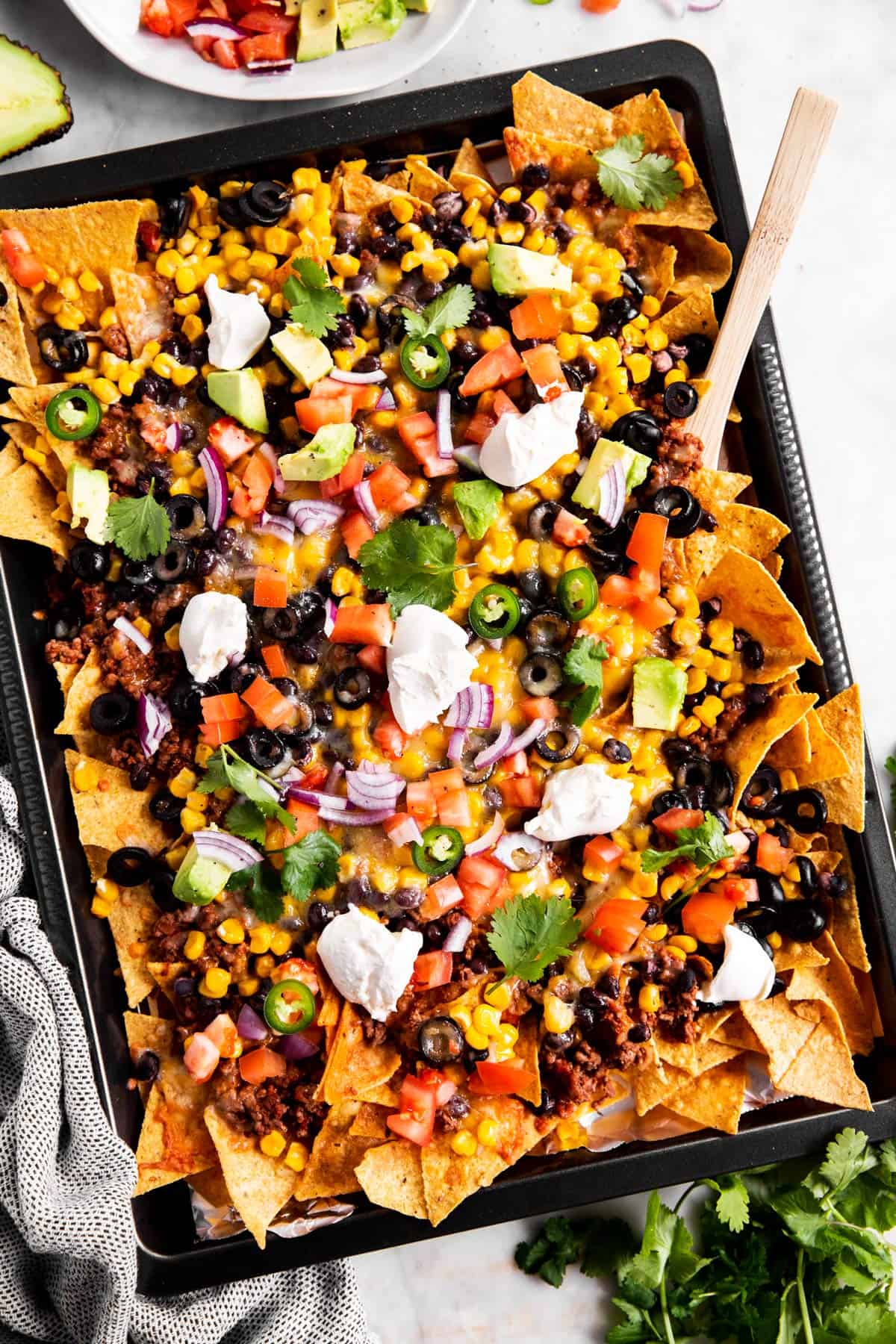 sheet pan with nachos and toppings from above