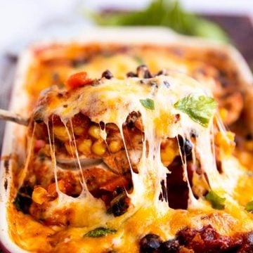 lifting a cheese covered chicken breast out of a casserole dish