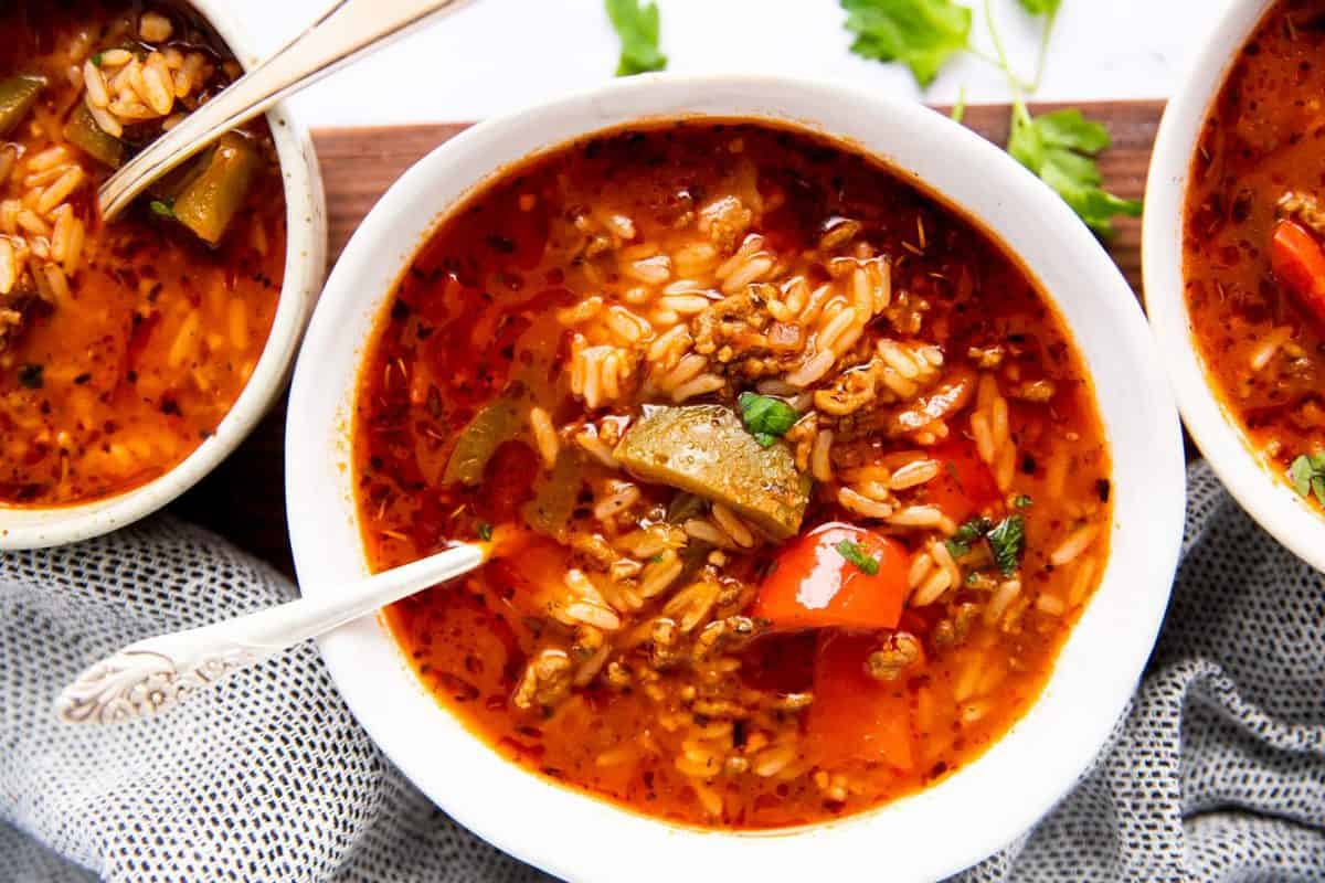 three white bowls with stuffed pepper soup on a wooden board