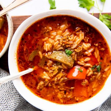 three white bowls with stuffed pepper soup on a wooden board