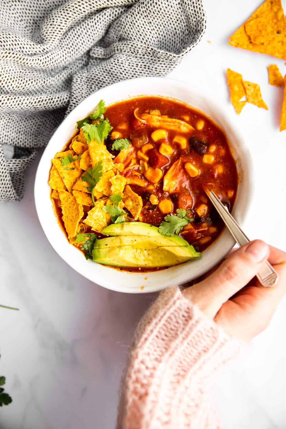 female Han holding spoon in white bowl of chicken taco soup