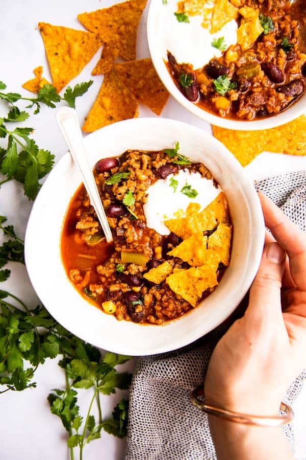 top down view on female hand holding a bowl of chili