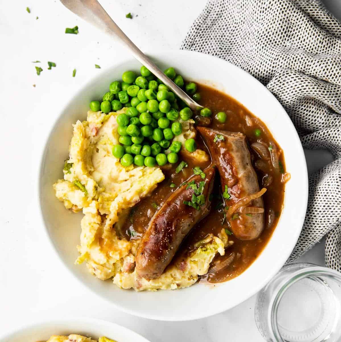 top down view of white plate with bangers and mash