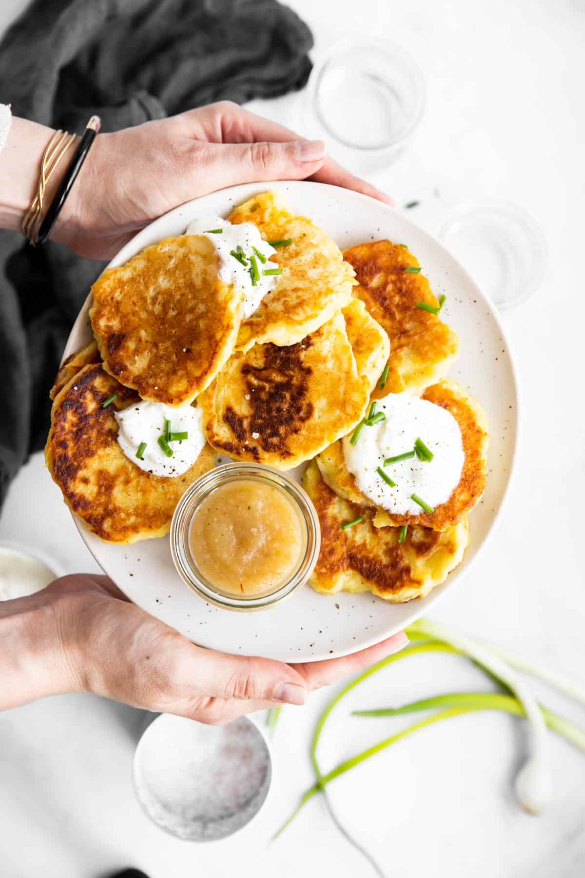 female hands holding a plate with potato pancakes