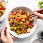female hands holding a plate with chicken lo mein