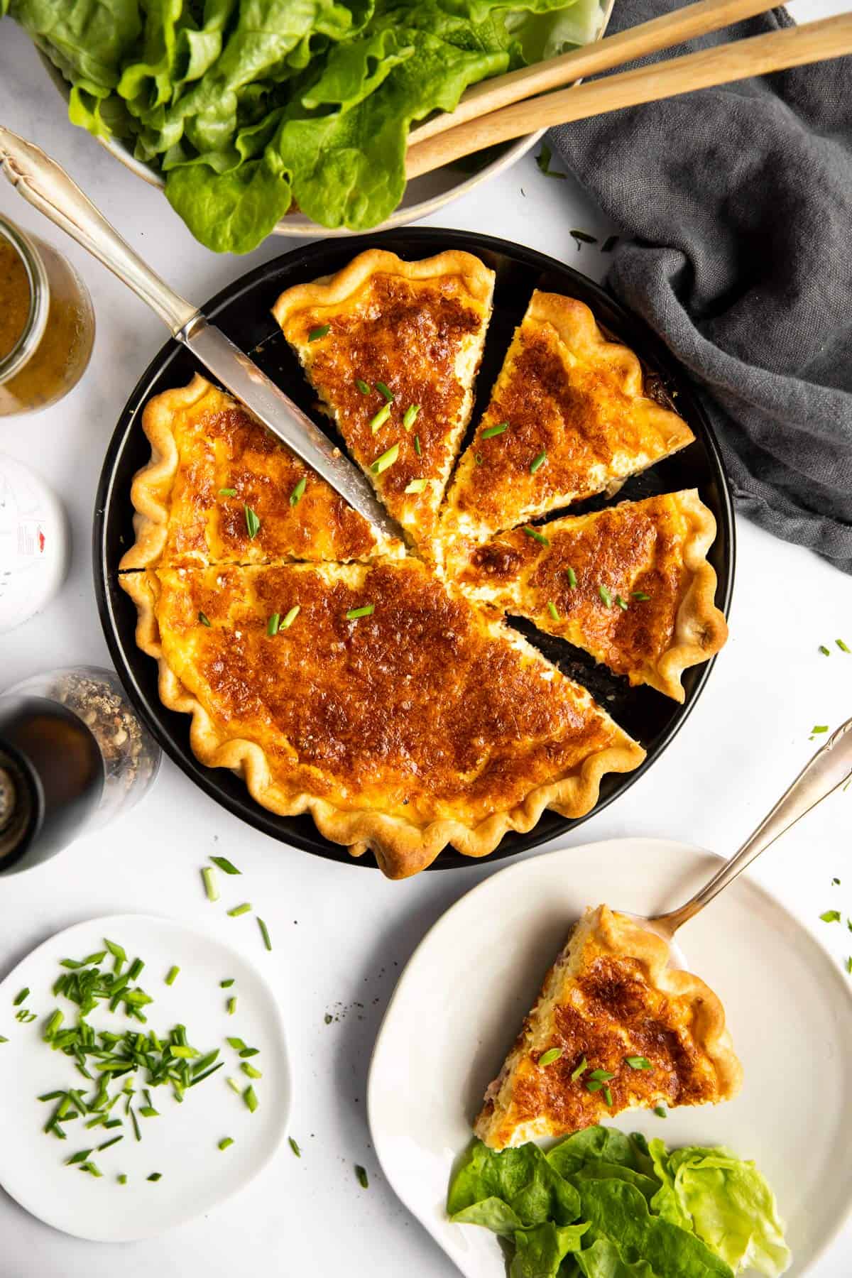 top down view on sliced Quiche Lorraine on a set table with salad