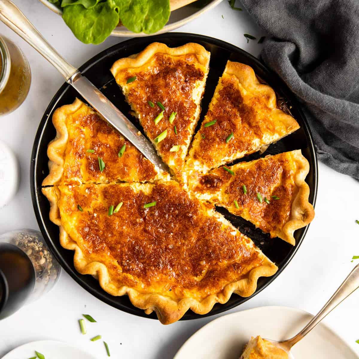 top down view on sliced Quiche Lorraine on a set table with salad