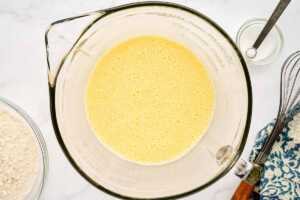 Whisked eggs and milk in glass bowl.