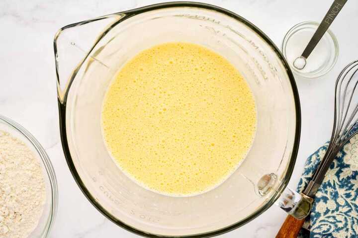 Whisked eggs and milk in glass bowl.