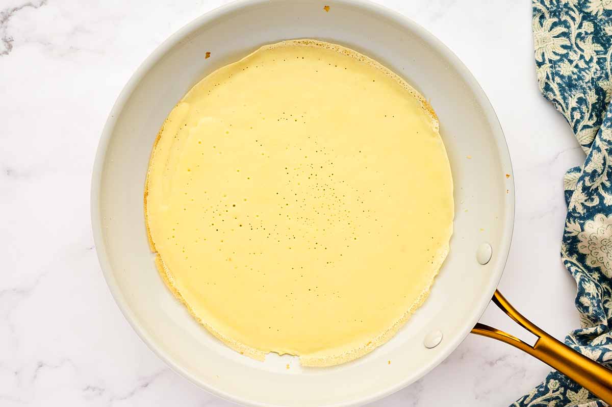 Half baked crêpe in pan.