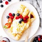 top down view on plate with crepes, whipped cream and berries