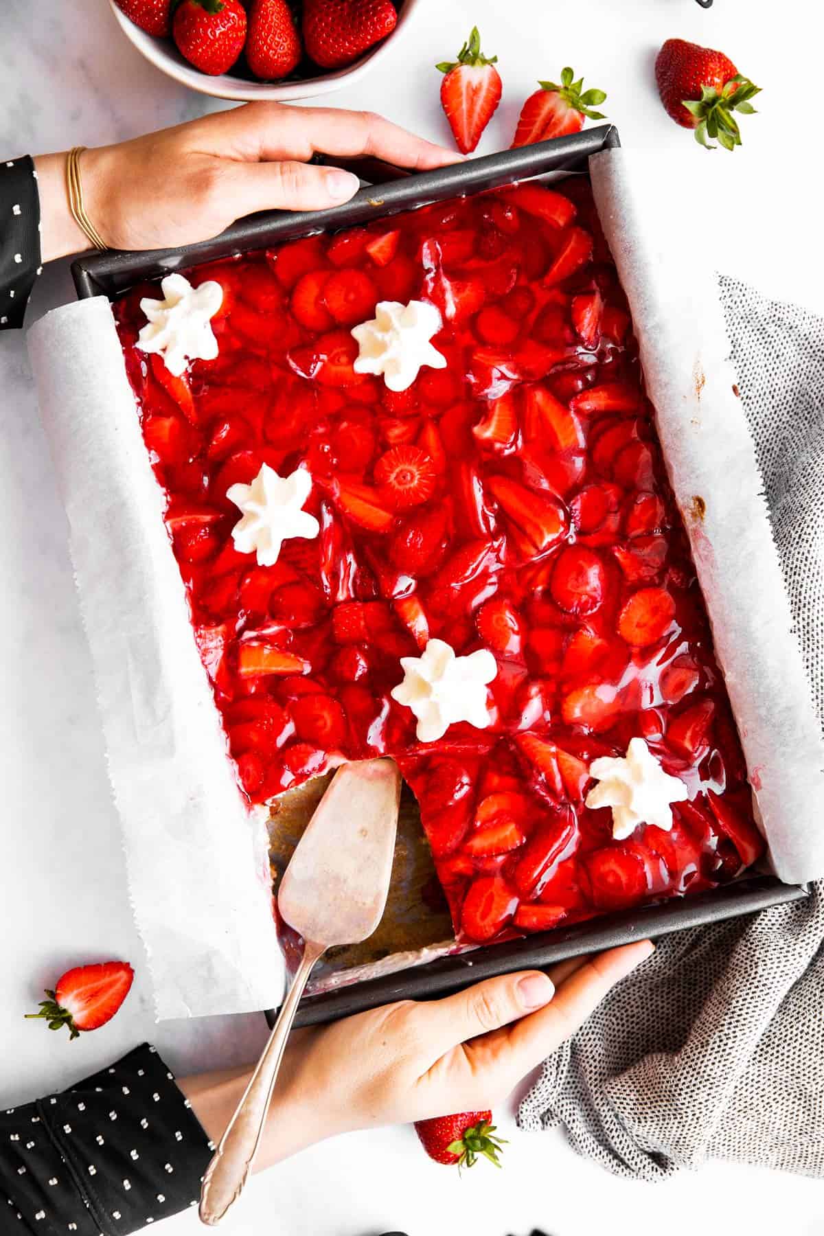 top down view on female hands holding cake pan with strawberry cake