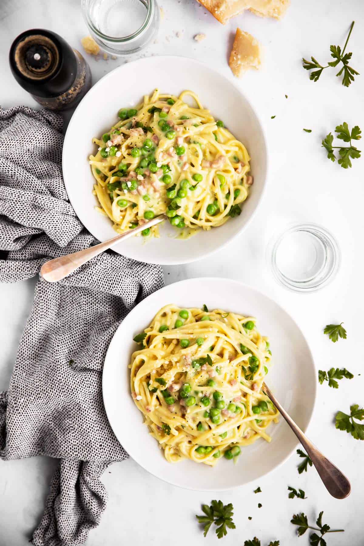 two plates with ham and pea spaghetti