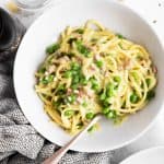 overhead view of ham and pea pasta in white plate