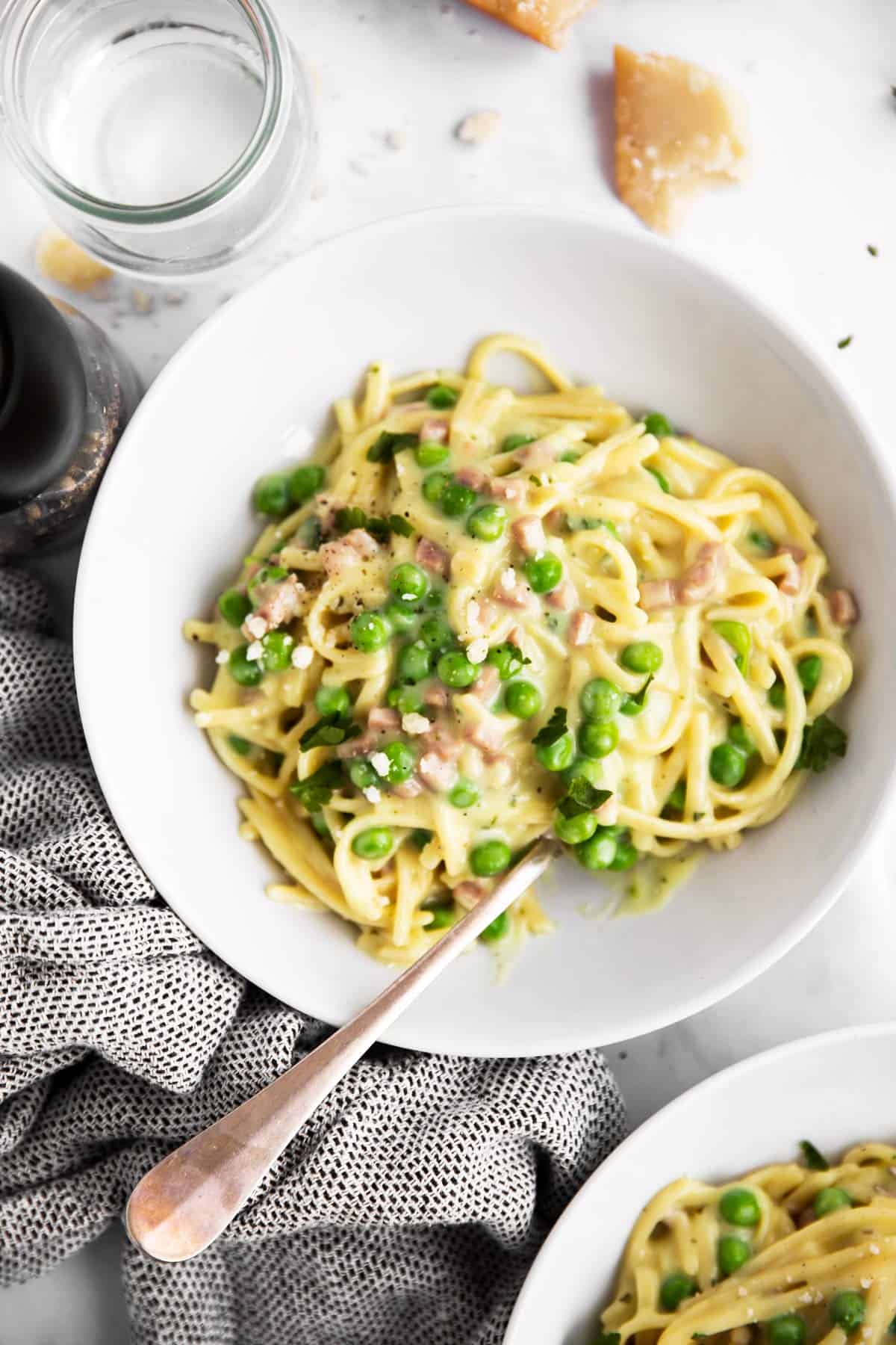 overhead view of ham and pea pasta in white plate