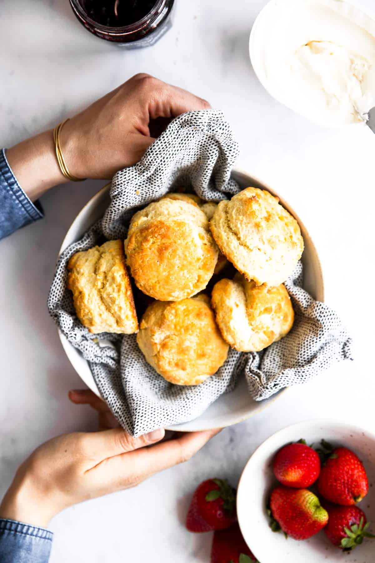 woman holding a basket with biscuits on a table