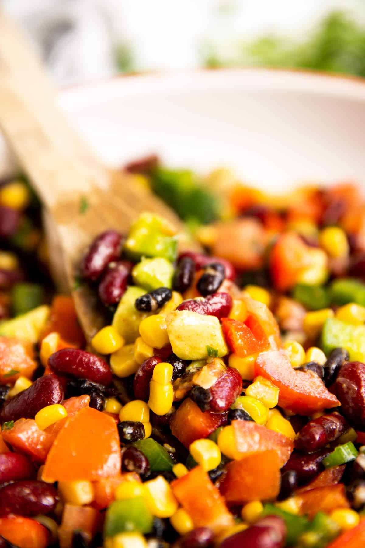 scooping Mexican salad with a wooden salad tong