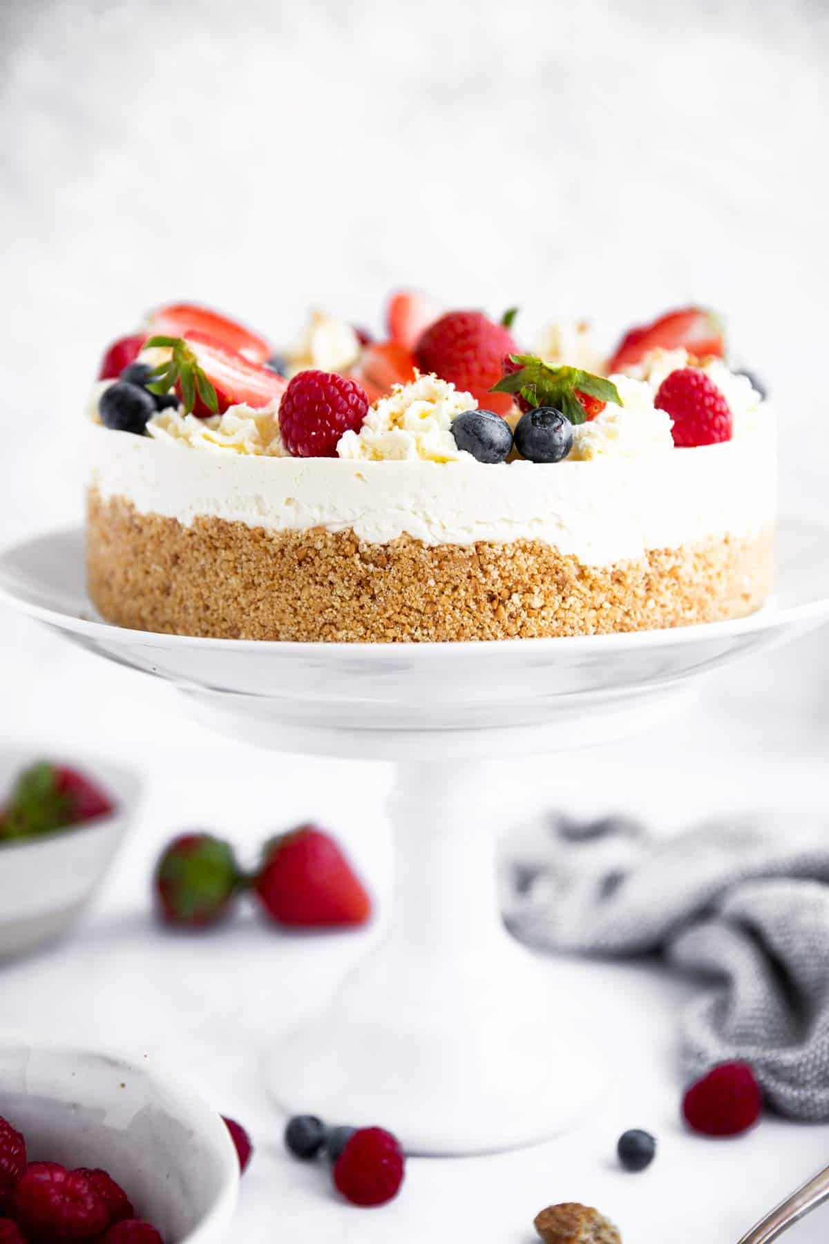 no bake cheesecake decorated with berries on a cake stand