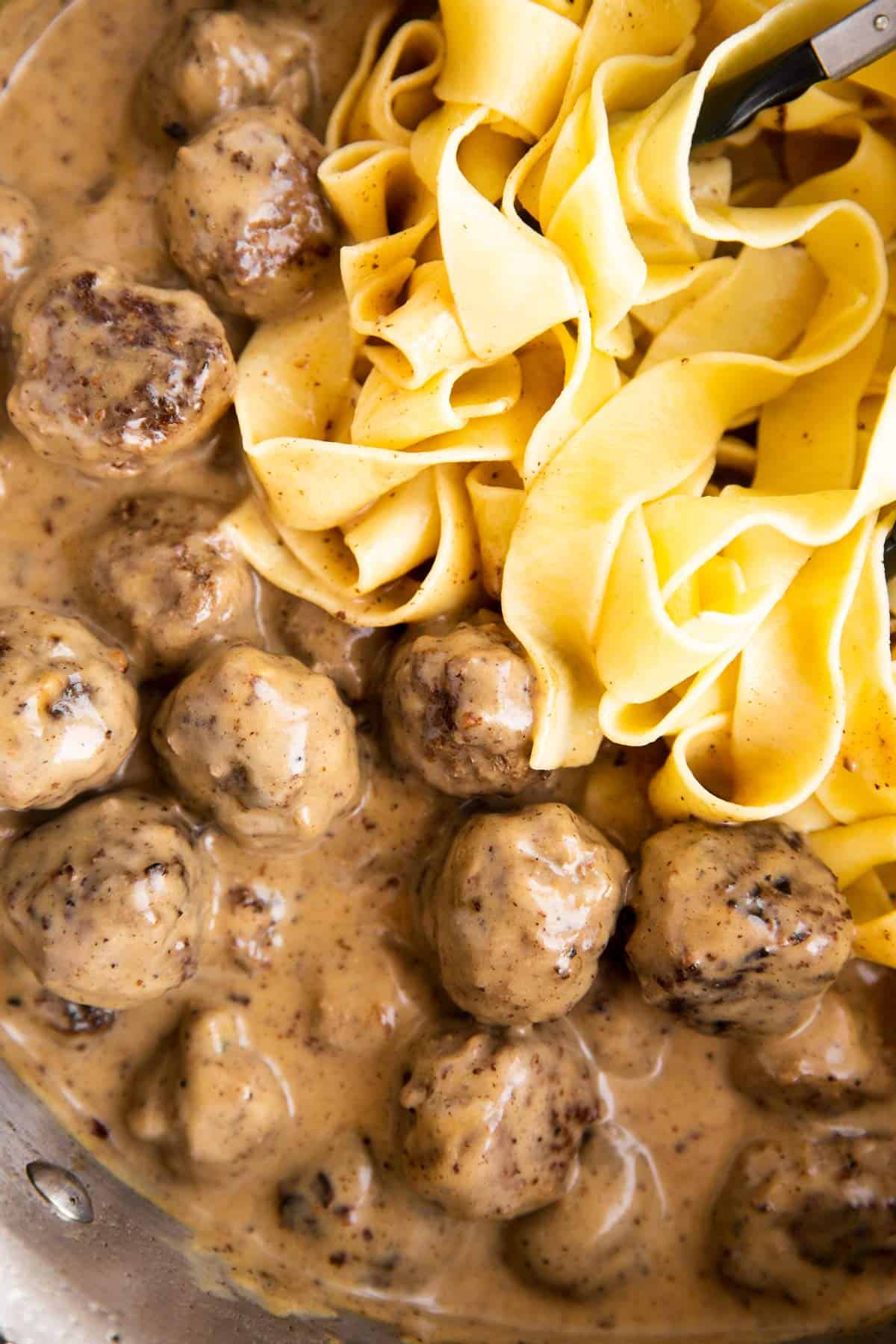 close up photo of meatballs in gravy next to egg noodles