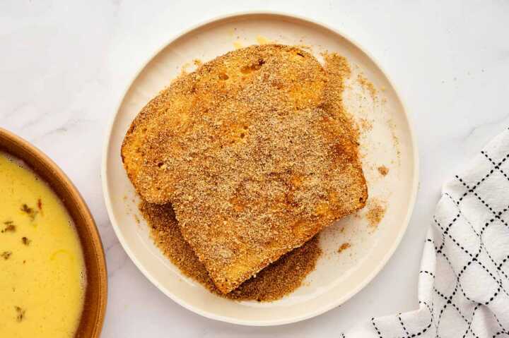 Coating French toast in cinnamon sugar and breadcrumbs.