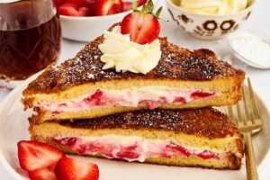 Serving stuffed French toast with strawberries and whipped cream.