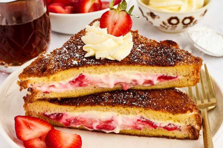 Serving stuffed French toast with strawberries and whipped cream.