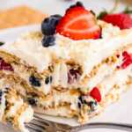 frontal closeup of berry icebox cake on plate with bite taken out
