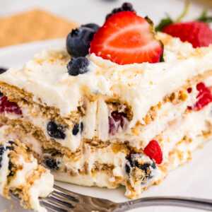 frontal closeup of berry icebox cake on plate with bite taken out