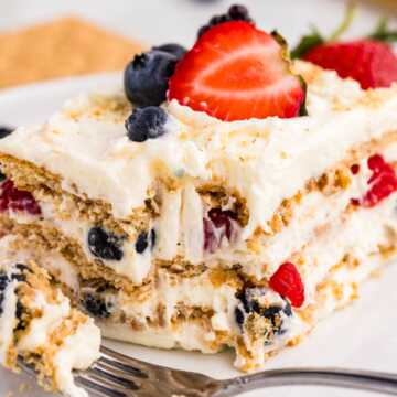 frontal closeup of berry icebox cake on plate with bite taken out
