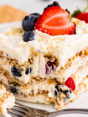 frontal closeup of berry icebox cake on plate with bite taken out