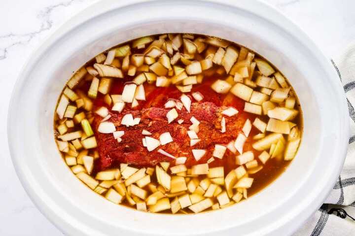 Uncooked pork shoulder in slow cooker.